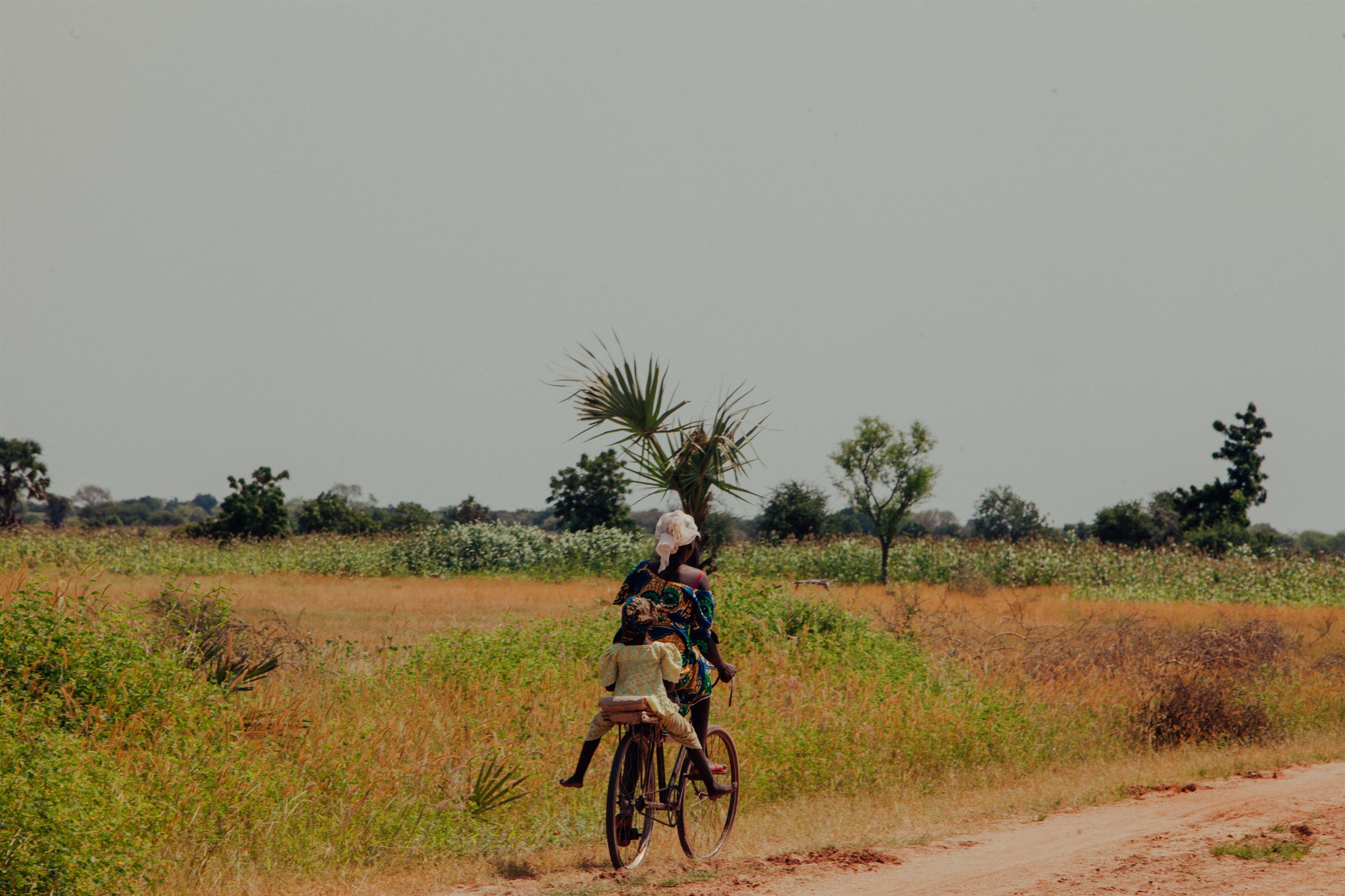 A woman carrying a child walks across open farmland