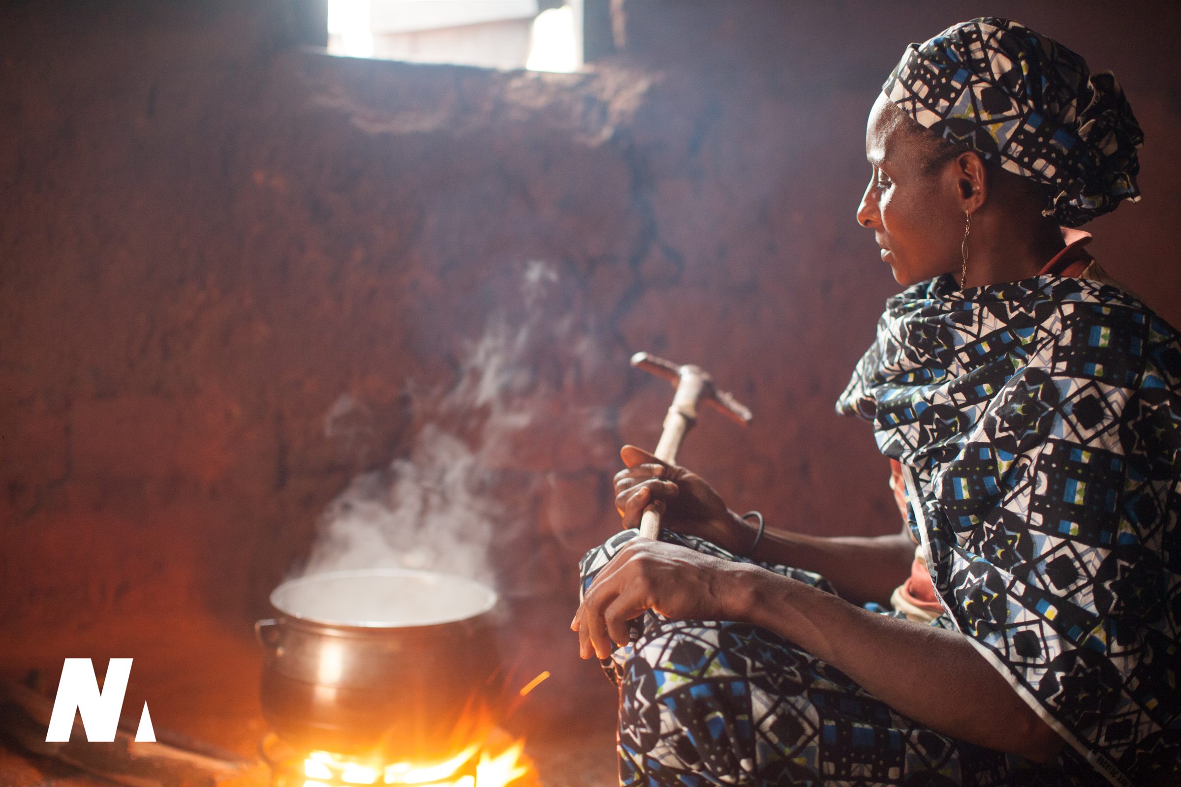 A woman preparing food beside a cooking fire