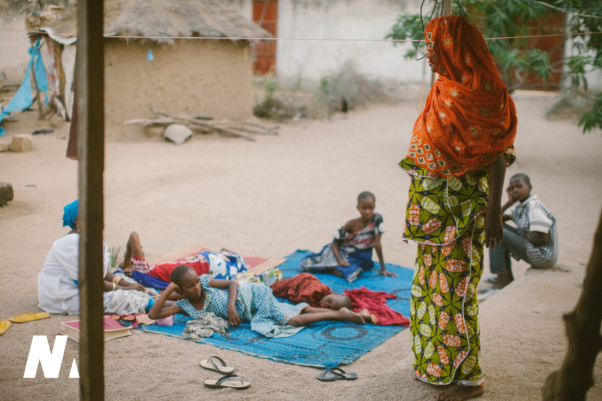 A woman standing beside children resting together outdoors