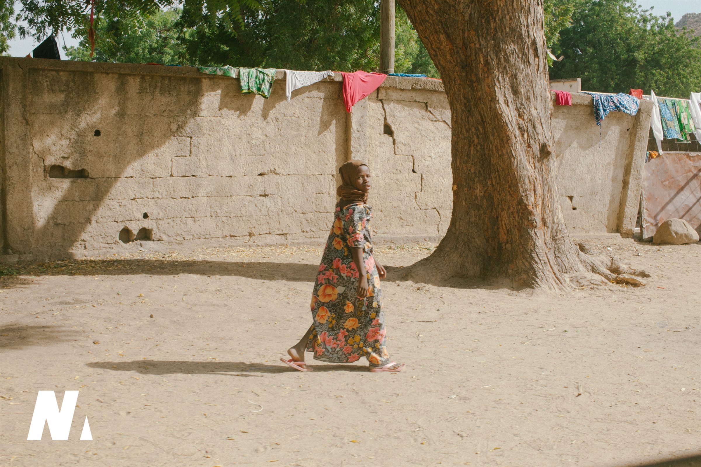 A woman walking beneath a broad shade tree
